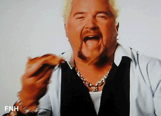 Celebrity chef, Guy Fieri, excitedly takes a bite of a pizza slice.