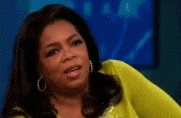 Gif of Oprah, a black woman with straight, black hair, greenish yellow top, and hoop earrings, shaking her head in No.