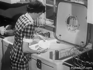 A woman loads dishes into a machine. A woman loads dishes into a machine.