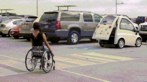 femme en fauteuil roulant qui rentre dans dans sa voiture qui est adaptée à son handicap. Elle rentre par le coffre qui s'ouvre entièrement et automatiquement.