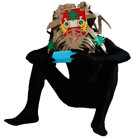 Seated figure holding a small blue object, wearing a large ornate cardboard headdress