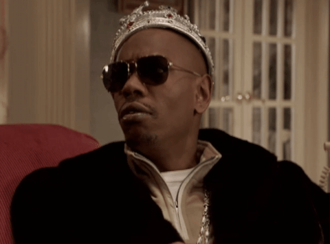 gif of a man sitting on a couch with a crown and sunglasses. He has a lot of money because he spends less living in shared housing