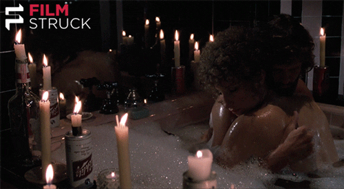 Couple hugging in a bathtub with candles lit around