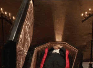 A vampire rises out of his coffin dramatically, only to bang his head on a low-hanging chandelier.