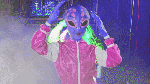 A brightly colored alien in a pink tracksuit vogues for the camera.