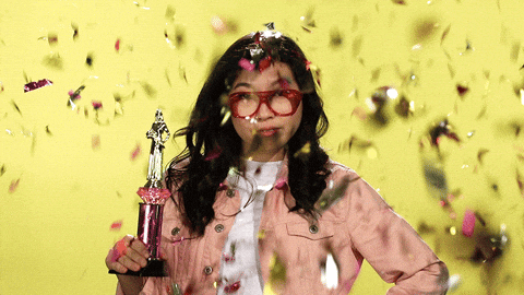Femme qui tient un trophée et reçoit des confettis. 