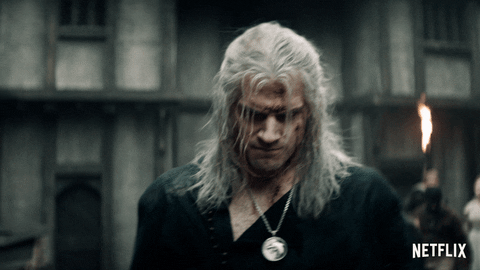 Geralt de Rivia, personagem da série The Witcher, caminhando de cabeça baixa com machucados em seu rosto.