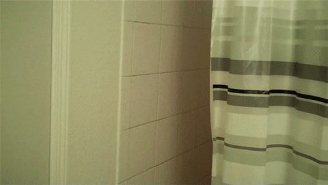 Unhappy guy frowning from behind the shower curtain