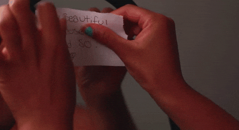 Spiegel wo eine dunkelhäutige Frau einen Zettel anklebt mit dem Text: I am beautiful because I said so