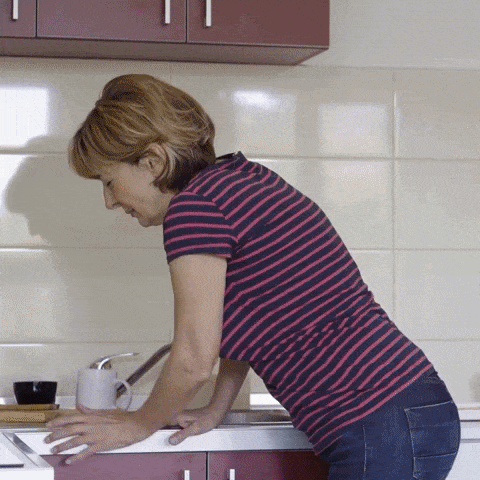 Kvinne som står på beina og får vondt i ryggen