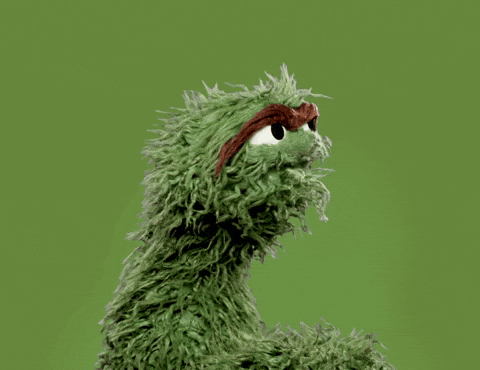 Furry green muppet ,Oscar the grouch, shakes his head in disbelief, against a light green background.
