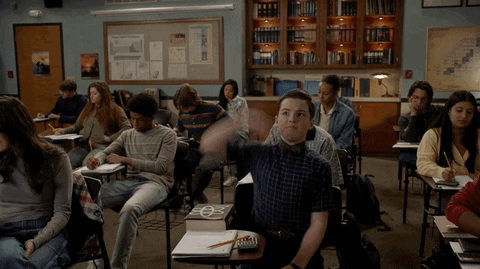 trecho da série Young Sheldon em que o personagem principal está em aula levantando a mão para fazer uma pergunta