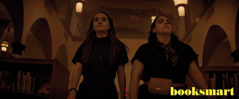 Gifs of two girls, Amy and Molly strutting through a library in jumpsuits
