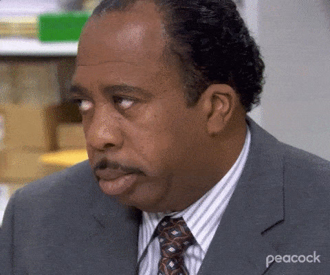 The Office: Stanley Hudson, in a suit and tie, rolls his eyes upward and stares, unimpressed.