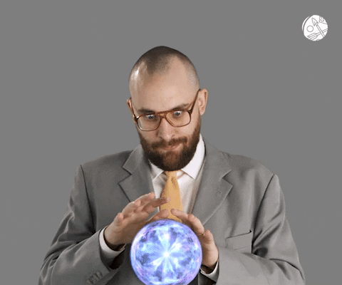 Guy in a suite with crazy eyes waving hands over crystal ball
