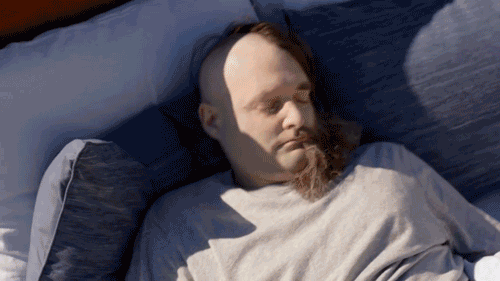 GIF of man rolling out of a bed at the top of a cliff and landing in a cushion below