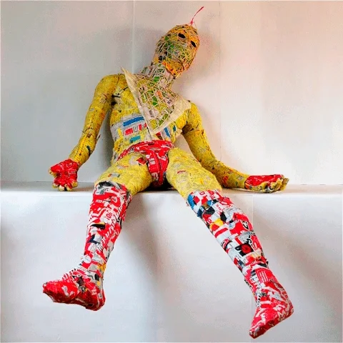 Collapsed seated figure whose whole body is wrapped in printed paper