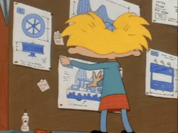 arnold from hey arnold standing back after pinning a blueprint on a wall