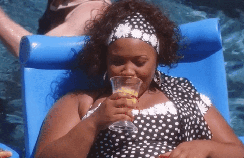 a GIF of a black woman lounging in a pool with a drink