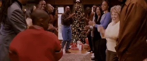 People dancing and clapping with a lit Christmas tree in the background