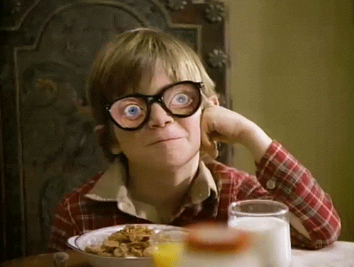 enfant qui prend son petit déjeuner et qui porte des lunettes avec des gros yeux 